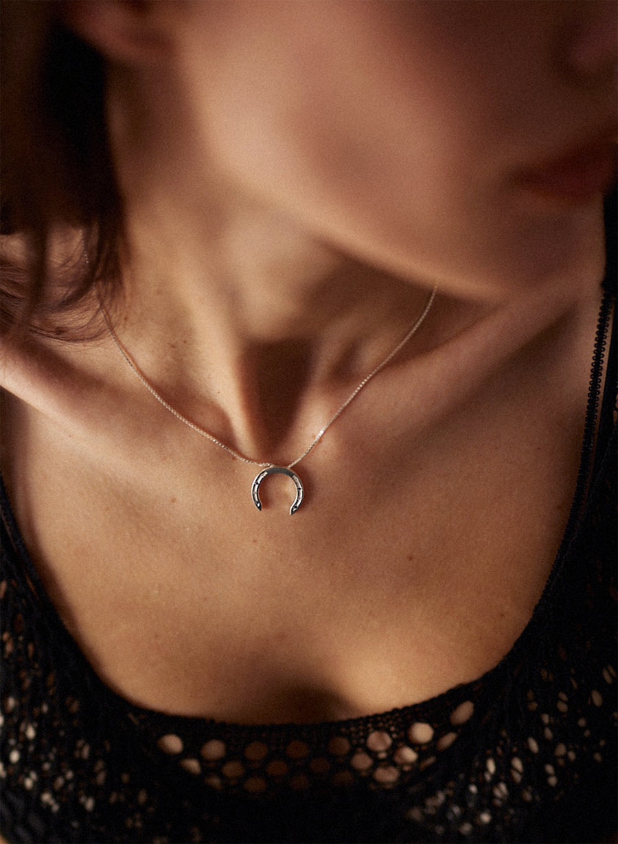 women wearing horseshoe necklace in silver.